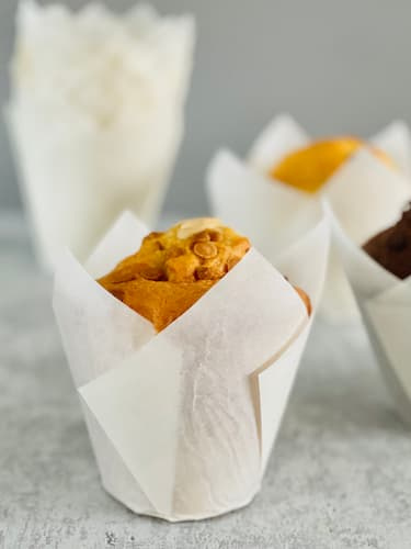 Upieczone muffinki w białych papilotkach tulipan – dekoracyjna prezentacja deserów